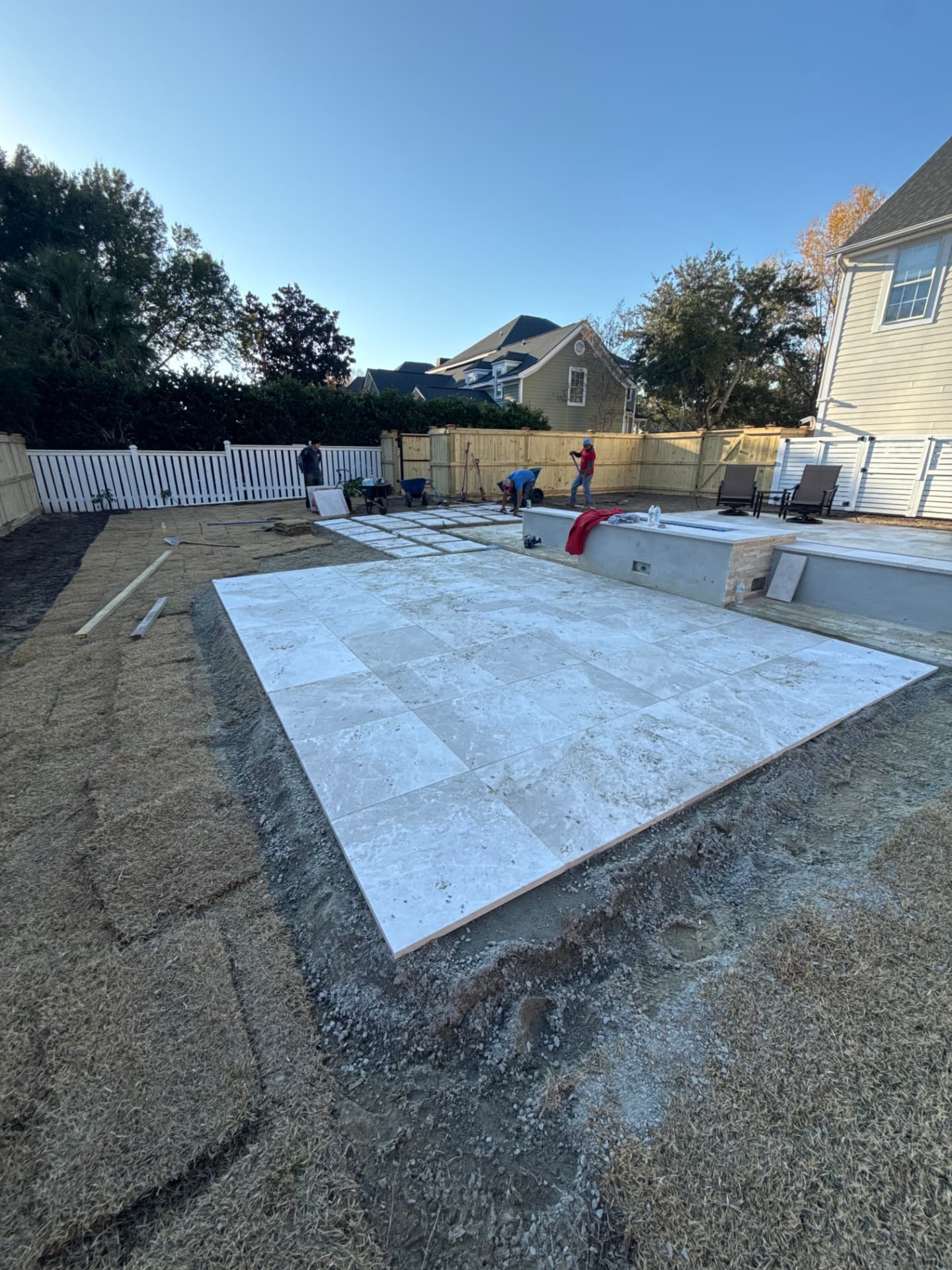 Newly laid travertine patio with fire feature in a fenced backyard