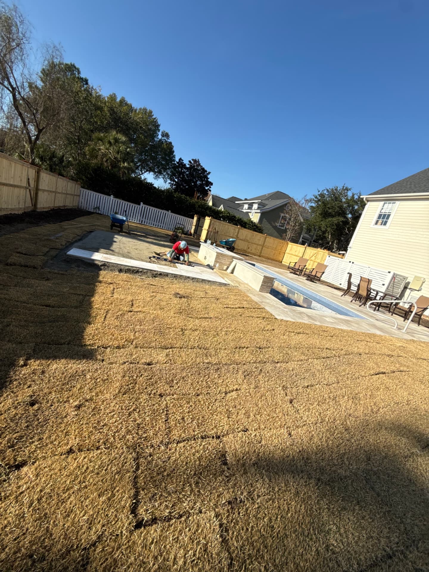 Freshly laid sod and concrete decking around a backyard pool